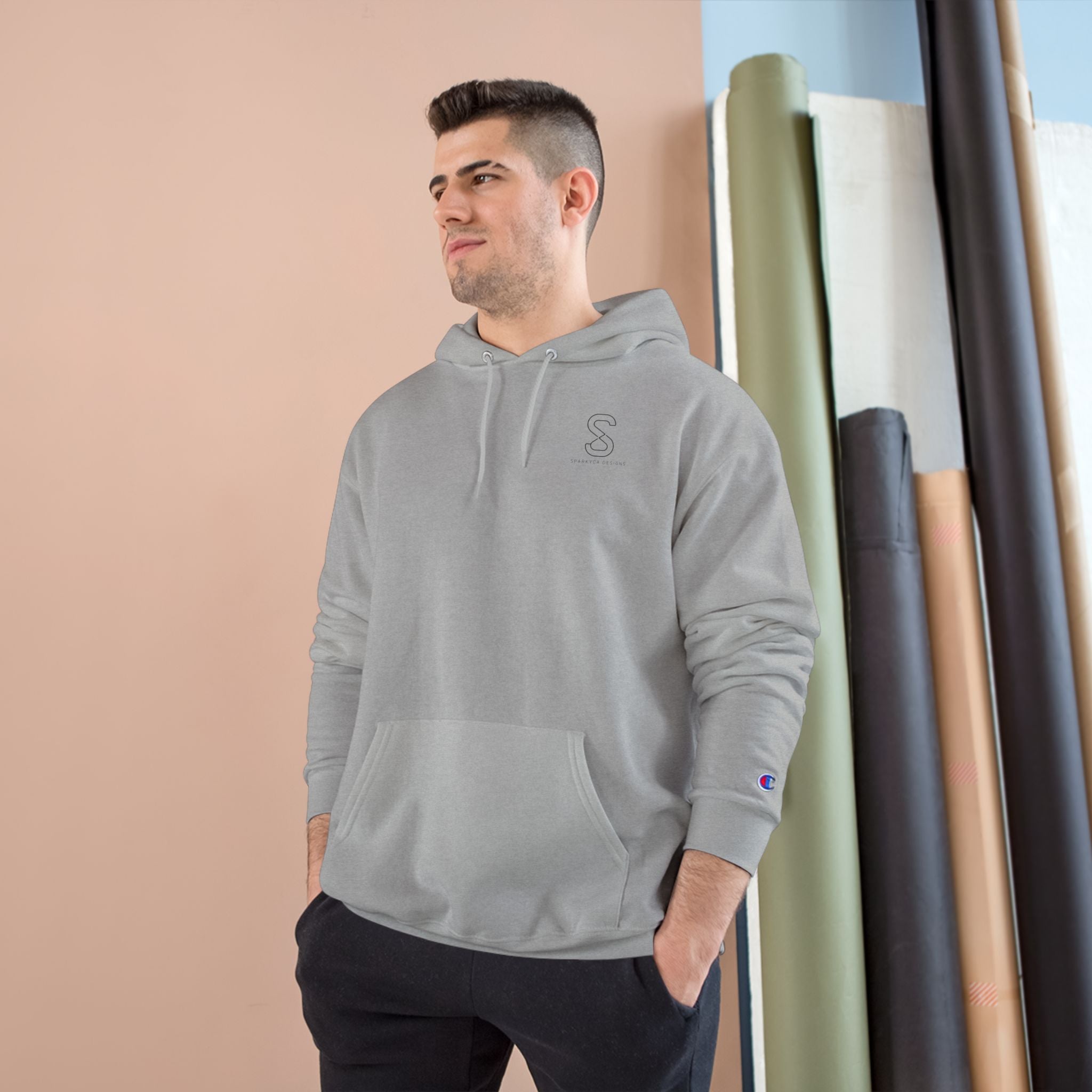 Man wearing the light steel grey SparkyCA Champion hoodie, hands in pockets