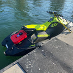 Green Sea-Doo Spark Trixx docked on the water with a red fuel can mounted on the back