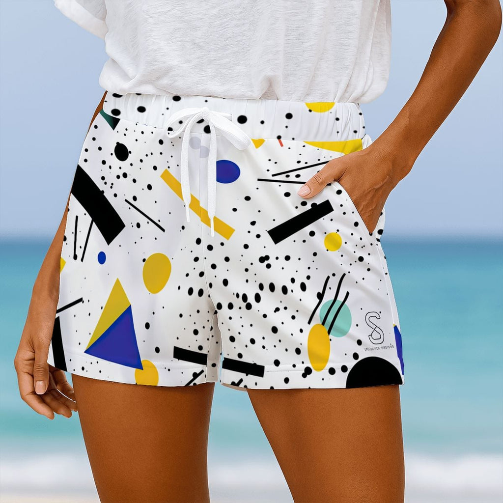 White beach shorts with black polka dots and colorful geometric shapes, close-up on model