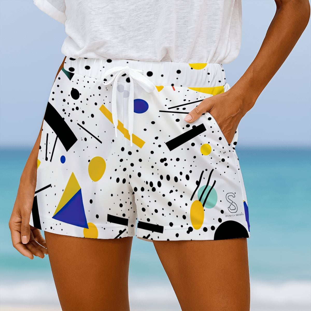 White beach shorts with black polka dots and colorful geometric shapes, close-up on model