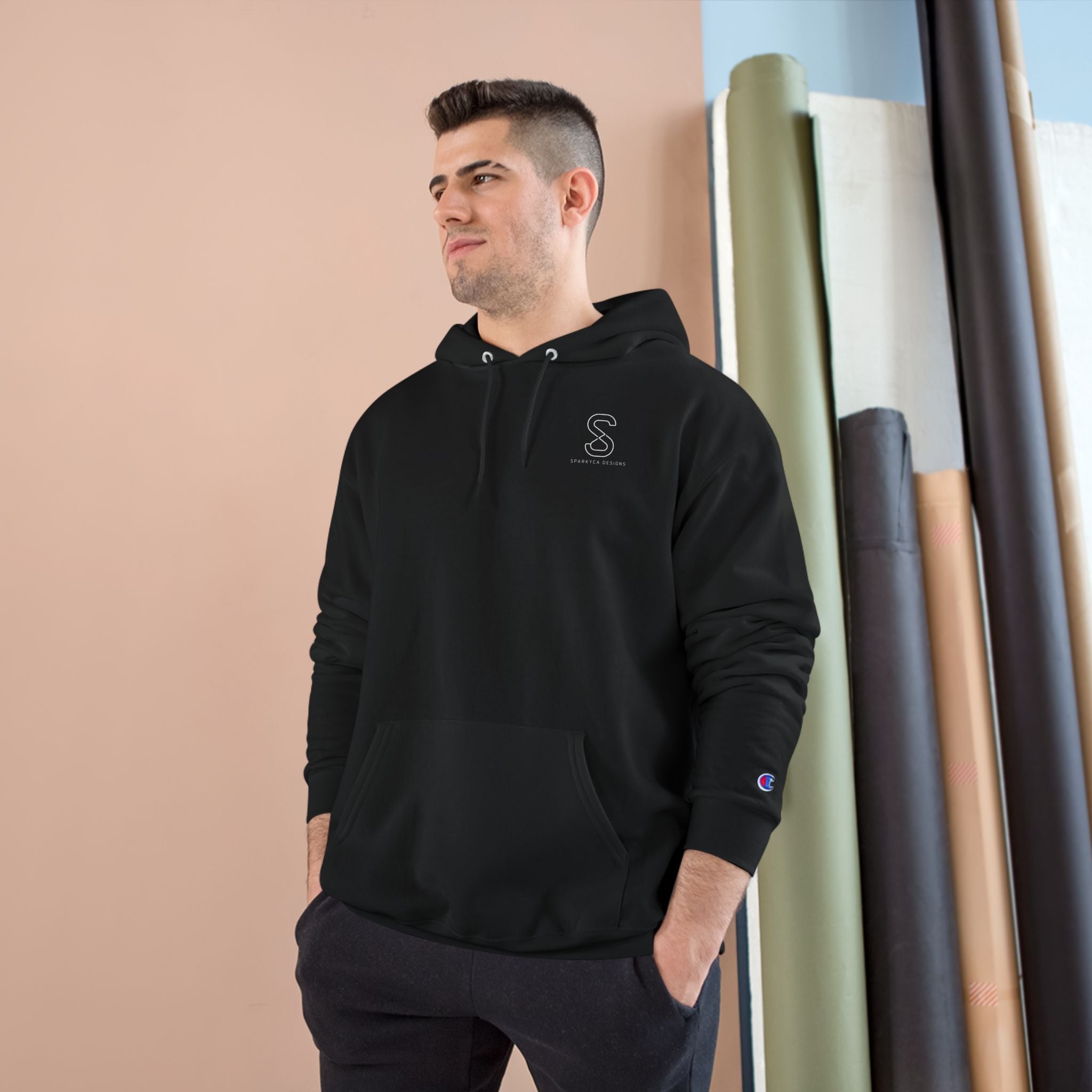 Man wearing the black SparkyCA Champion hoodie, hands in pockets