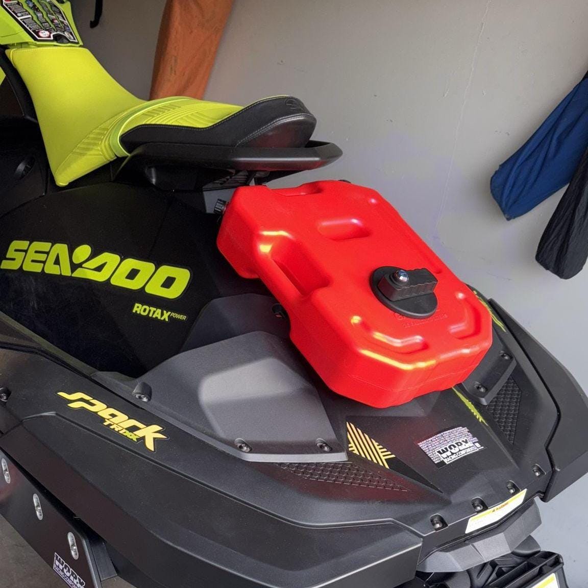 Red fuel can mounted on a Sea-Doo Spark parked in a garage