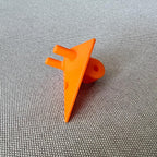 Orange 3D-printed GoPro mount on a woven fabric surface, angled view showing mounting holes