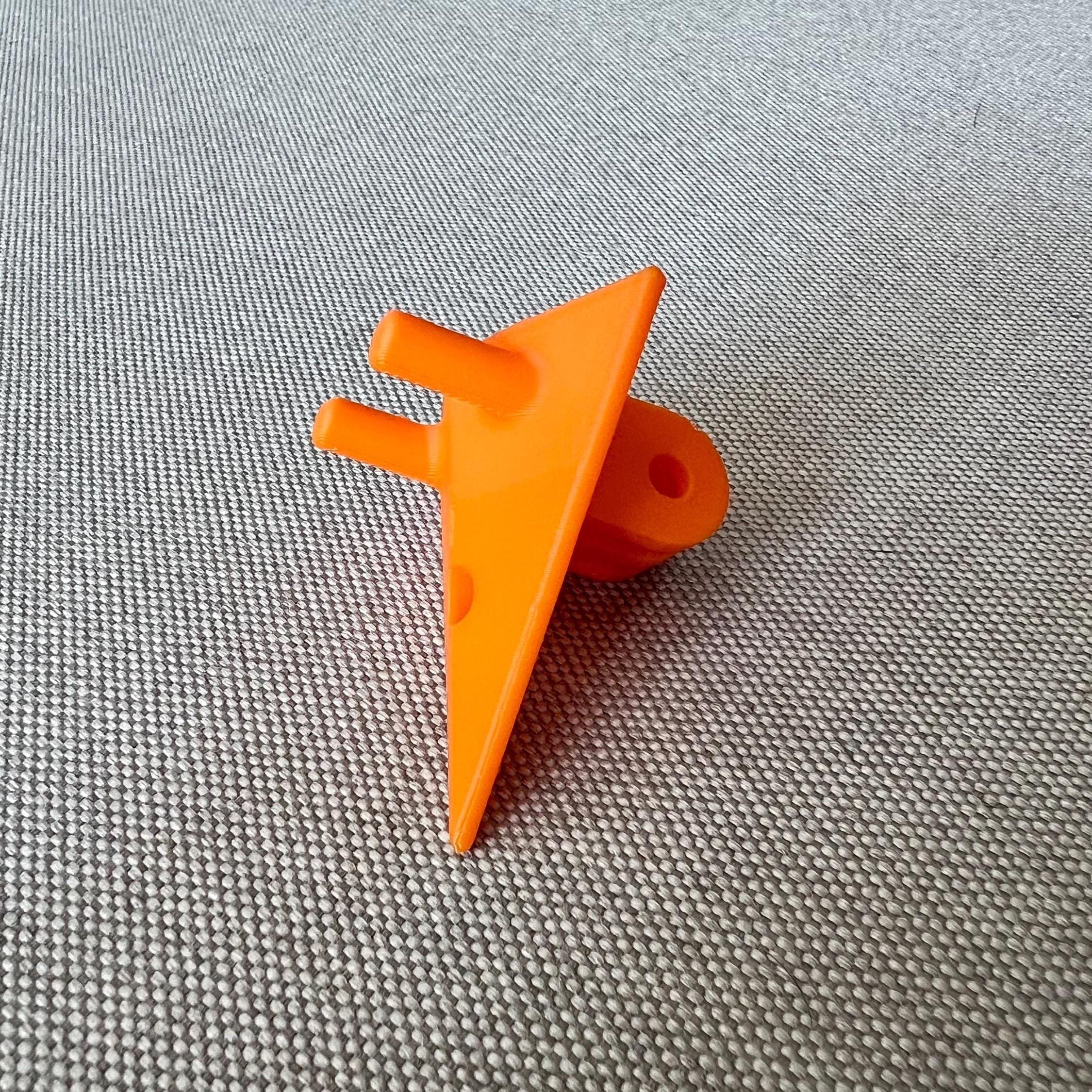 Orange 3D-printed GoPro mount on a woven fabric surface, angled view showing mounting holes
