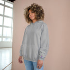 Woman wearing the light steel grey SparkyCA Champion hoodie beside a window