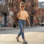 Woman wearing peach SparkyCA t-shirt with jeans on a city street