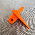 Orange 3D-printed GoPro mount on a woven fabric surface, top-down view