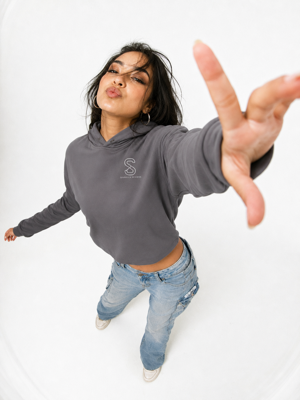 Woman wearing the Women's Cropped Hoodie in Storm grey, playful studio photo