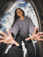Woman wearing the Women's Cropped Hoodie in Storm grey, city skyline lifestyle photo
