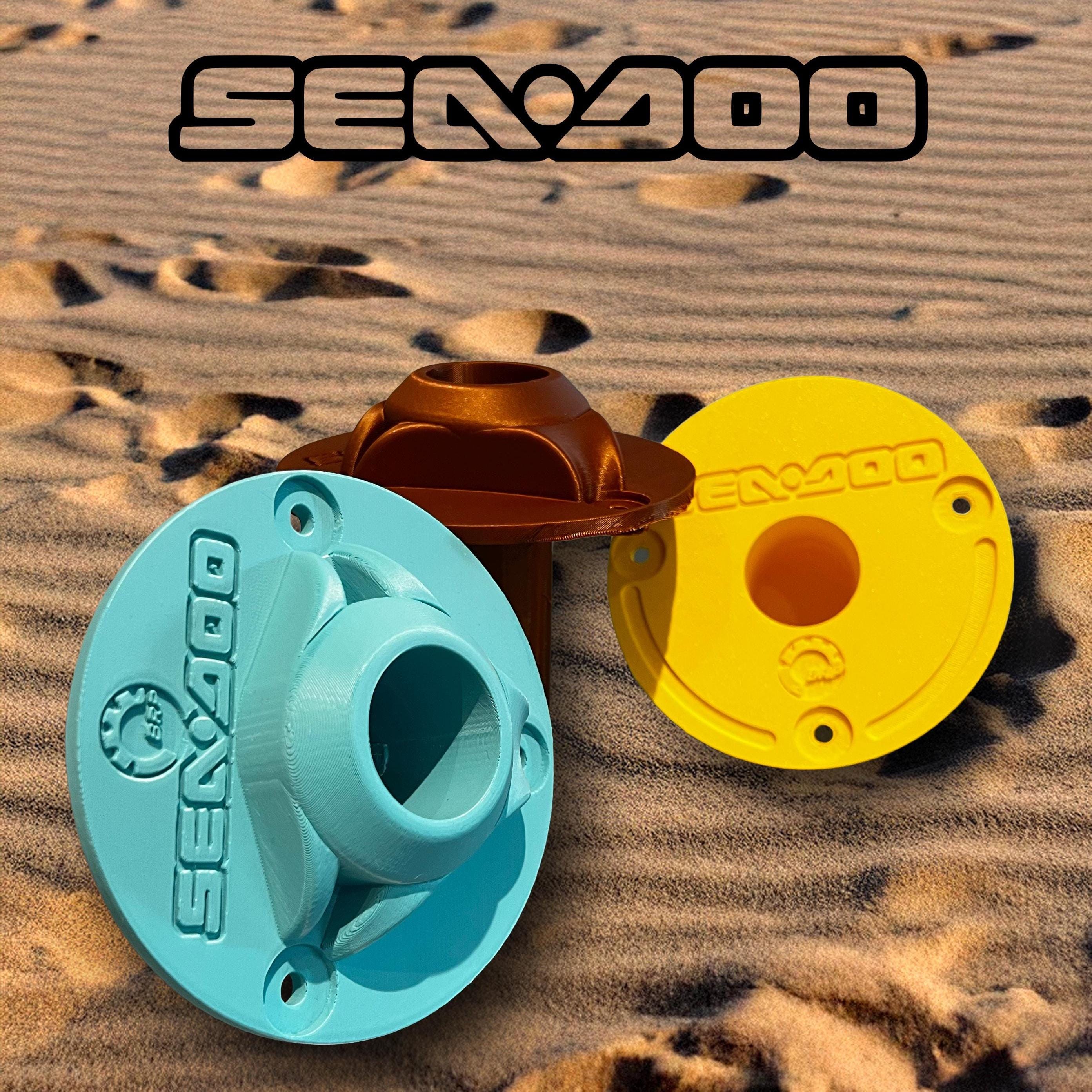 Bronze, teal, and yellow Sea-Doo Insta360 pole mounts grouped together on sand