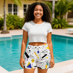 Woman wearing white geometric-print beach shorts and a white top, poolside