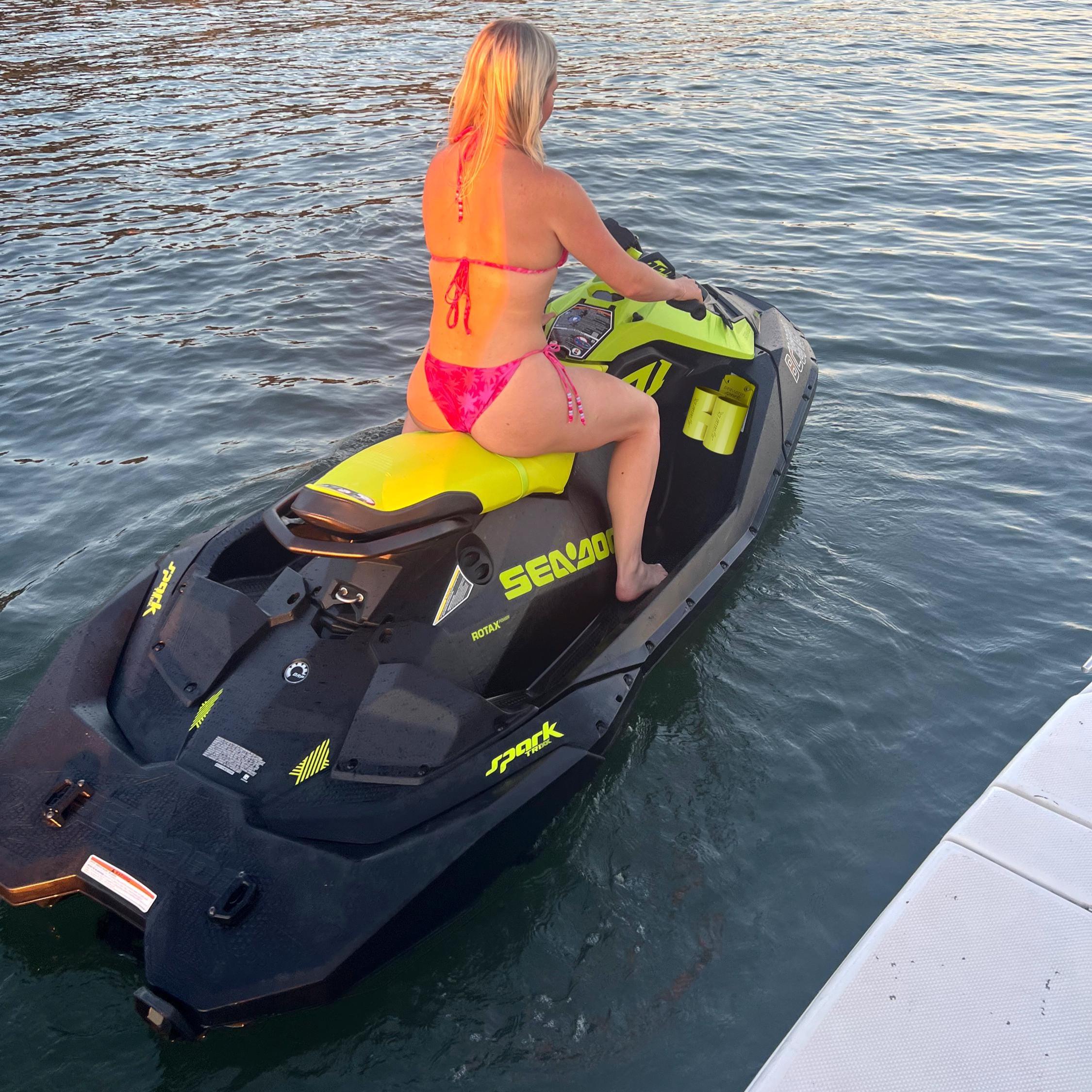 Yellow Sea-Doo Spark Trixx cup holder mounted on the rear deck, rider seated at the dock at sunset