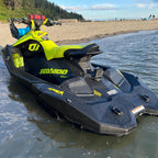 Yellow cup holder mounted on a Sea-Doo Spark Trixx beached on sand, with a red cup inside