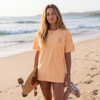 Woman wearing the SparkyCA Designs Classic Crewneck Tee in Orange, beach lifestyle photo with a skateboard