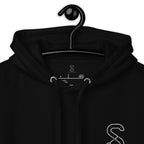 Close-up of the black hoodie's inner neck label showing the SparkyCA Designs logo, size, and made-in-Pakistan fabric tag