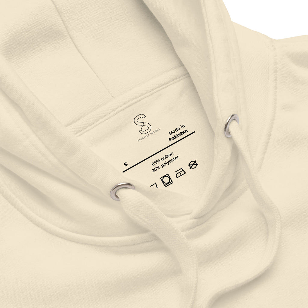 Close-up of the Bone hoodie's inner neck label showing the SparkyCA Designs logo, size, and made-in-Pakistan fabric tag