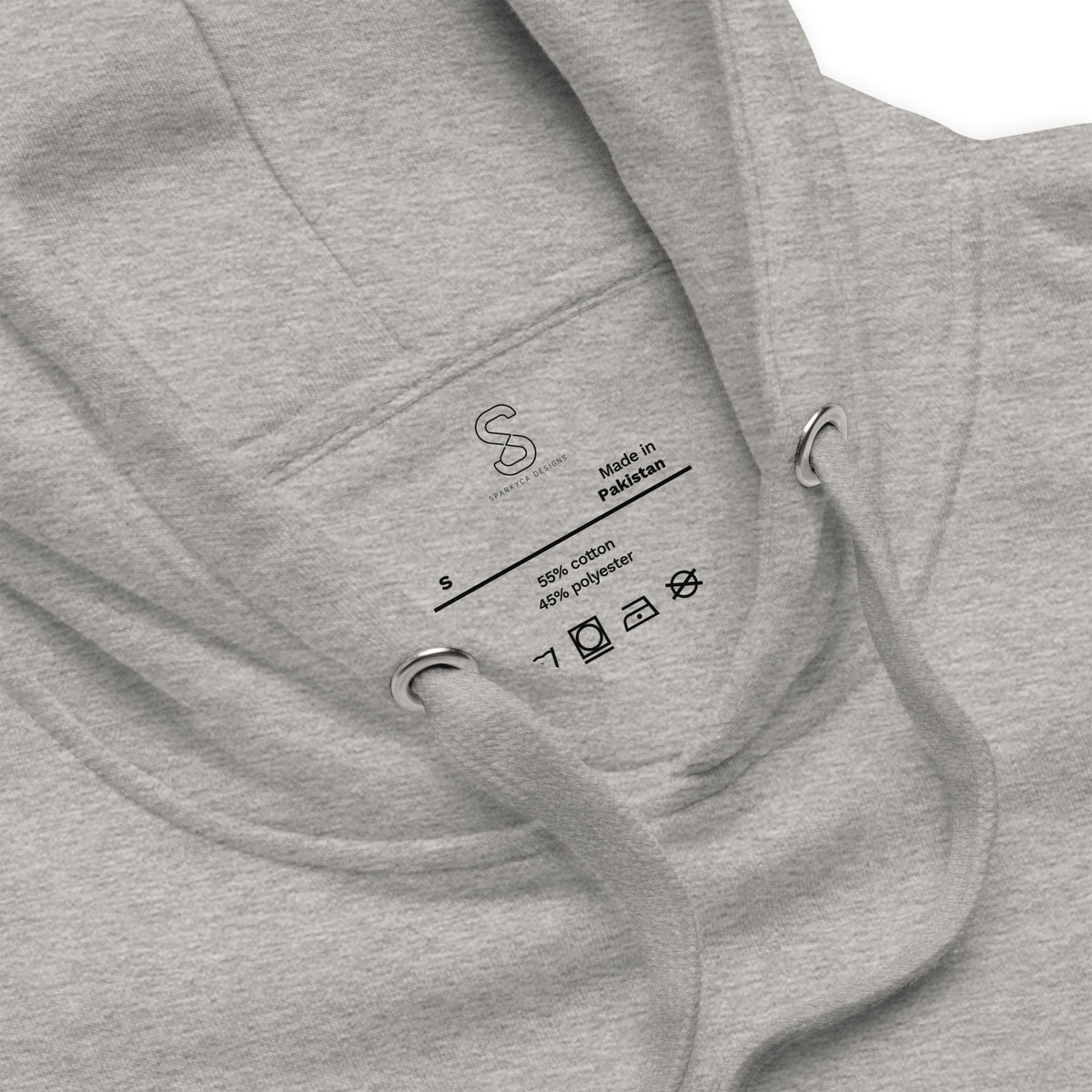 Close-up of the Carbon Grey hoodie's inner neck label showing the SparkyCA Designs logo, size, and made-in-Pakistan fabric tag