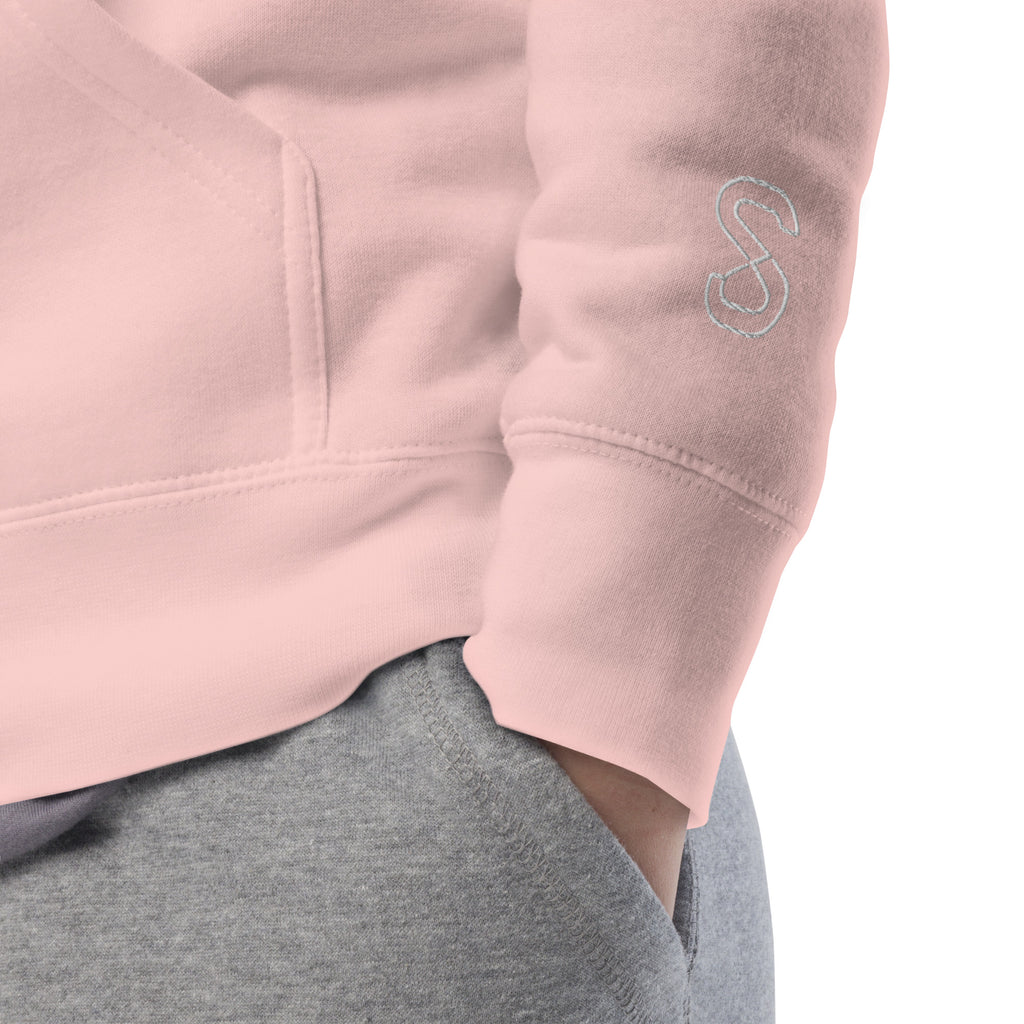 Close-up of the Light Pink hoodie's inner neck label showing the SparkyCA Designs logo, size, and made-in-Pakistan fabric tag