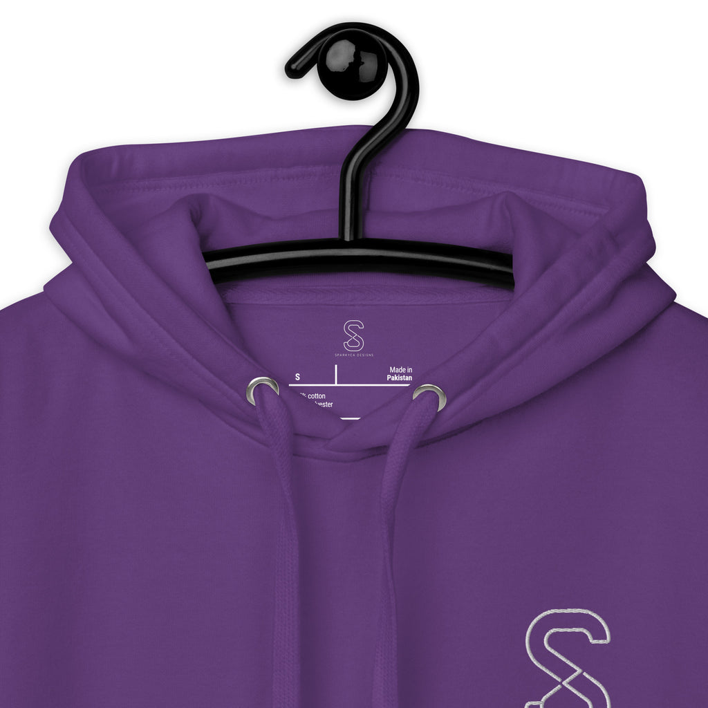 Close-up of the purple hoodie's inner neck label showing the SparkyCA Designs logo, size, and made-in-Pakistan fabric tag