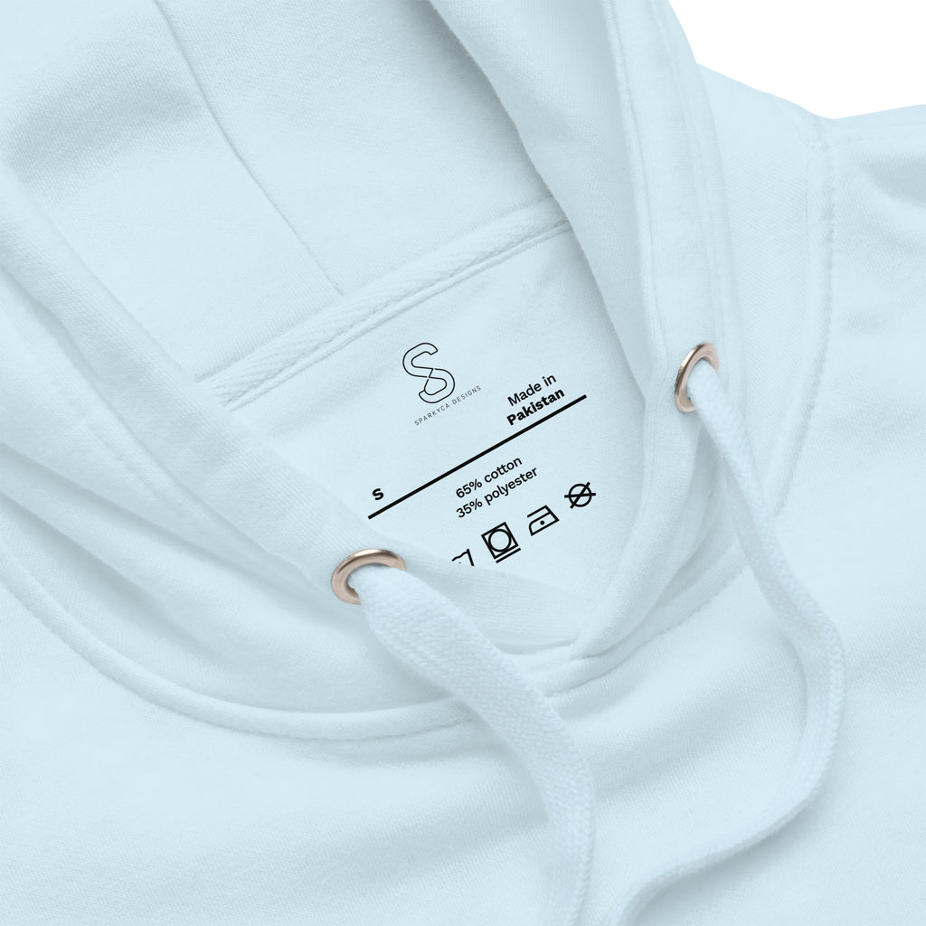 Close-up of the Sky Blue hoodie's inner neck label showing the SparkyCA Designs logo, size, and made-in-Pakistan fabric tag