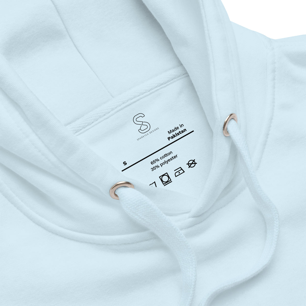 Close-up of the Sky Blue hoodie's inner neck label showing the SparkyCA Designs logo, size, and made-in-Pakistan fabric tag