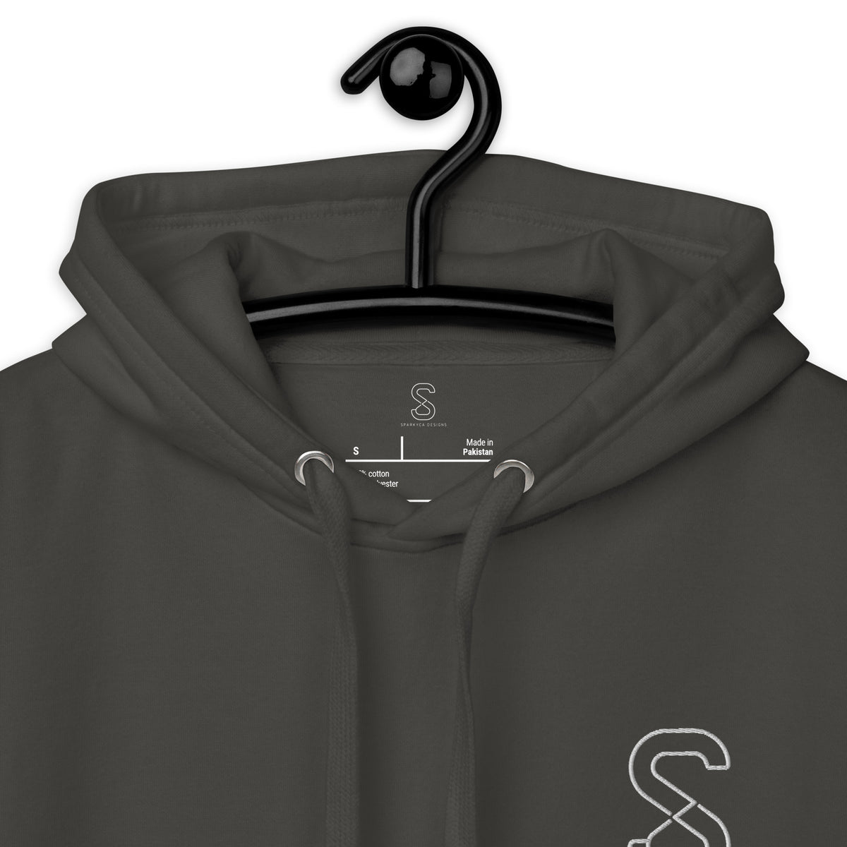 Close-up of the Vintage Black hoodie's inner neck label showing the SparkyCA Designs logo, size, and made-in-Pakistan fabric tag